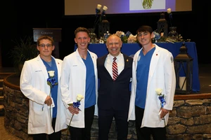 Each student is coated by a senior nursing major, members of the class of 2025. From left to right, Isaiah Hatcher, Ian Fowler, President Brad Johnson, and Mason Cole. 